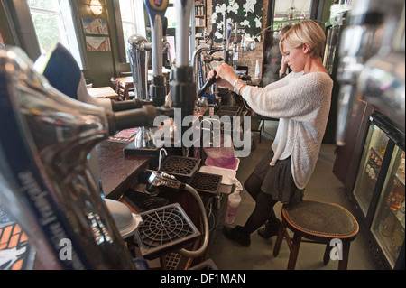 Eine Bardame, die Reinigung der Rohre, ein neues Fass Bier in einem Pub in Brighton, England. Stockfoto