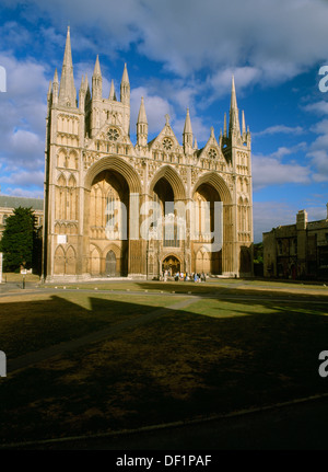 NW-Turm & Westfassade von Peterborough Kathedrale (St.-Peter Kirche) mit frühen englischen Gotik Bildschirm Wand & flankierenden Türmen. Kirchgänger in der Sonne. Stockfoto