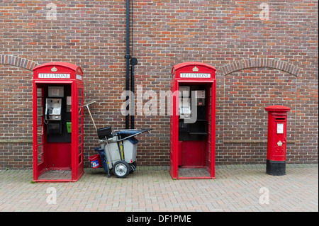 Zwei traditionelle rote Telefonzellen, eine rote Säule-Box und ein sauberer Wagen. Stockfoto