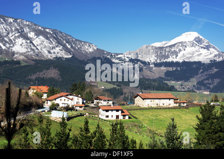 Dorf im Aramaio Tal, umgeben von schneebedeckten Bergen, im Baskenland. Stockfoto