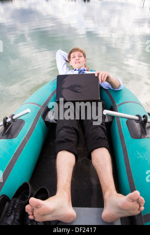 Gekleidete Mann lag im Boot und nehmen Sie sich Zeit Stockfoto