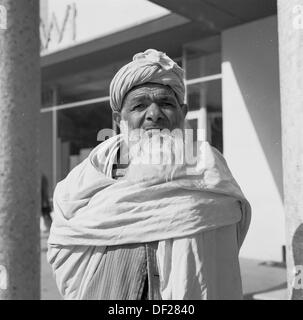 Historisches Bild aus den 1950er Jahren von J Allan Cash eines älteren bärtigen afghanischen Mannes in Kabul, Afghanistan, umwickelt mit einem traditionellen Baumwoll- oder Stoffgewand um ihn herum und mit Bart und Kopfschmuck. Stockfoto