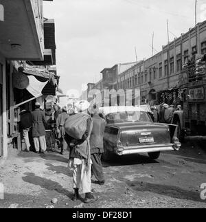 Historisches Bild aus den 1950er Jahren von J Allan Cash, das eine geschäftige Straßenszene in Kabul, Afghanistan, zeigt. Die 1950er und 1960er Jahre waren eine relativ friedliche Zeit, da Anstrengungen unternommen wurden, um ein gewisses Maß an Modernisierung zu erreichen und das Land zu einer offeneren, wohlhabenderen Gesellschaft zu machen. Dies endete in den 1970er Jahren mit Invasionen, Staatsstreichs und Bürgerkriegen. Stockfoto