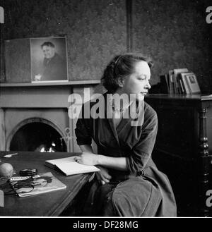 Historisches Bild von einer jungen Dame sitzt an einem Tisch in einem Salon mit ihrem Tagebuch und eine Fotografie-Magazin der 1950er Jahre. Stockfoto