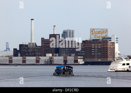 Wasser-Taxi überqueren Innenhafen, Domino Zucker Fabrikgebäude in Locust Punkt im Hintergrund, Baltimore, Maryland, USA Stockfoto