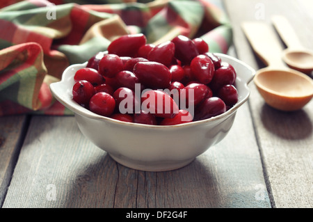 Frische reife Cornel Beeren in Schüssel auf hölzernen Hintergrund weiß Stockfoto