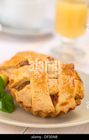 Kleine Runde Apfelkuchen mit Gitter-Kruste mit Minze auf einem Teller, heißer Apfel Schlag in den Rücken Stockfoto