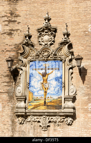 Azulejo zeigt Jesus am Kreuz auf einer Außenwand der Kirche der Mariä Verkündigung (Iglesia De La Anunciación) in Sevilla. Stockfoto