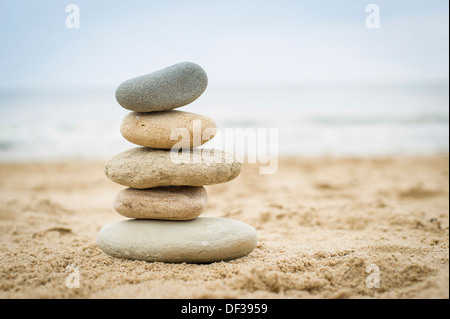Fünf Steinen ausgeglichen übereinander an einem Sandstrand Stockfoto