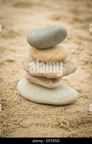 Fünf Steinen ausgeglichen übereinander an einem Sandstrand Stockfoto