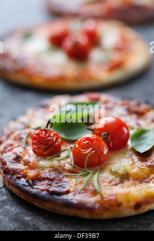 kleine Pizza mit Schinken, Speck, Käse und Tomaten Stockfoto