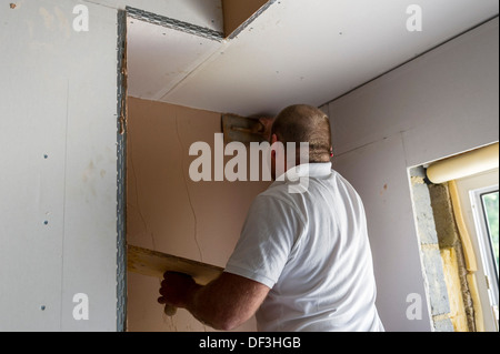 Ein Gipser arbeiten an einer Wand in einem Haus. Stockfoto