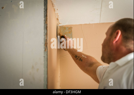 Ein Bauarbeiter mit einem Profil Kelle die Ecke der Wand zu glätten. Stockfoto