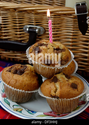 Muffins mit rosa Kerze vor Picknick-Korb, UK Stockfoto