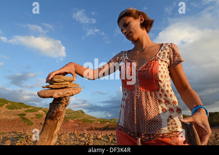 Junge Frau, die Gebäude einer Steinskulptur in Cala Pregonda, Menorca Stockfoto