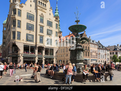 Menschen durch den Storch Brunnen auf Amagertorv Platz mit alten Gebäuden und St. Nikolaj-Kirche Turm Amager Torv, Kopenhagen Dänemark Stockfoto