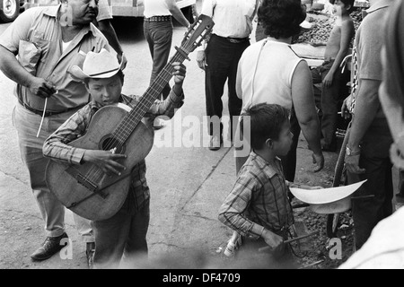 Mazatlan Mexiko. Kinder, die auf der Straße bummeln, Bruder, junger Bruder, der in seinem Hut sammelt und einen einfachen hölzernen Schlagzeugblock spielt. Mexikanischer Bundesstaat Sinaloa 1973. HOMER SYKES Stockfoto