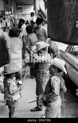 Mazatlan Mexiko 70er Jahre. Kinder bummeln in der überfüllten Straße, Bruder junger Bruder spielt einen einfachen hölzernen Schlagzeugblock und der jüngste spielt auf einer Blechdose. Mexikanischer Bundesstaat Sinaloa 1973. HOMER SYKES Stockfoto