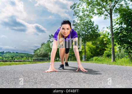 Urbane Sportarten - junge Frau tut Aufwärmen vor dem Ausführen in der grünen Wiese an einem Sommertag Stockfoto