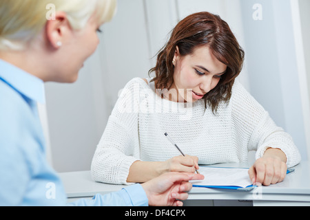 Patientin an der Rezeption der Arztpraxis medizinisches Formular ausfüllen Stockfoto