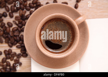 Tasse Kaffee, geöffneten Notizbuch und Kaffeebohnen auf Holztisch Stockfoto