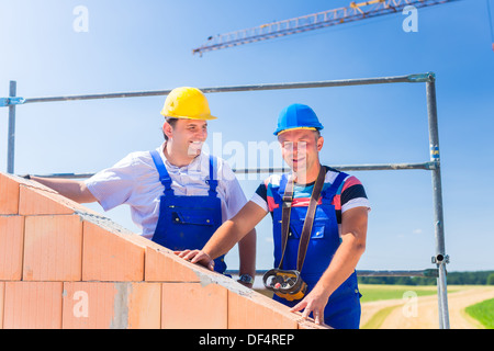 Zwei stolze Bauarbeiter Website oder Maurer auf Hausprojekt Regie des Krans mit einer Fernbedienung Stockfoto