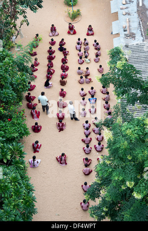 Blick hinunter auf eine Indian English Medium School mit Kindern Schneidersitz draußen zu sitzen. Puttaparthi, Andhra Pradesh, Indien Stockfoto