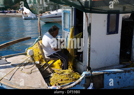 Fischer in seinem Boot Reparatur Fischernetze Halki Hafen Chalki Hafen Griechenland sitzen Stockfoto