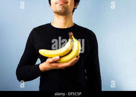 Junger Mann hält ein Bündel Bananen Stockfoto