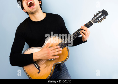 Glückliche junge Mann spielt Gitarre und singt Stockfoto