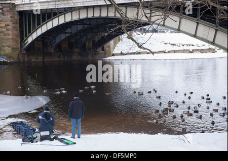 2 Männer im Schnee, Schnee, Schnee: Wintersport am Ufer des teilweise zugefrorenen Fluss Wharfe (1 Mann angeln mit großen keepnet, Rod & Zeile & männlich) - skipton, England, UK. Stockfoto