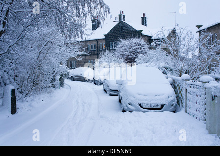 Winter Szene mit parkenden Autos außerhalb Doppelhaushälfte in einer ruhigen Wohnstraße, alle im Vertrag von frischem Schnee - Guiseley, England, UK. Stockfoto