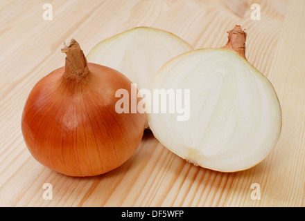 Ganze und geschnittene weiße Zwiebeln auf einem Holztisch Stockfoto