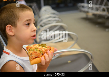 Junge am Flughafen - junge Pizza essen während des Wartens auf seiner Flucht Stockfoto