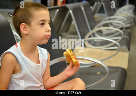 Junge am Flughafen - junge Pizza essen während des Wartens auf seiner Flucht Stockfoto