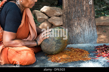 Indische Frau zerkleinern getrocknete rote Chili Pulver mit einem runden Stein in einem indischen Dorf. Andhra Pradesh, Indien Stockfoto