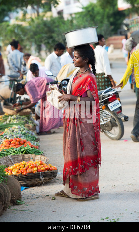 Armen niedrigere Kaste Indianerin auf einem Straßenmarkt mit einem Topf Reis auf dem Kopf die unverkäufliche Nahrung zu sammeln. Andhra Pradesh, Indien Stockfoto