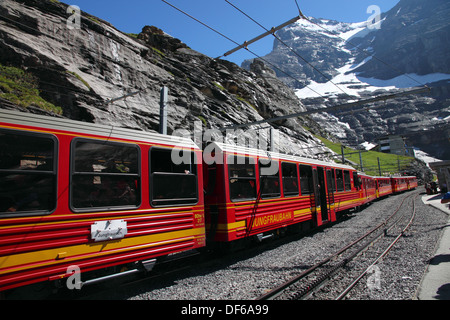 Ein roter Zug Jungfraubahnen an der Station Eigergletscher mit der Eiger in der Ferne. Stockfoto