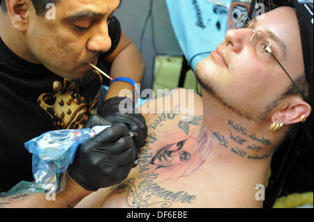 London, UK. 28. September 2013. Ein Tätowierer in die Liniengrafik eines Designs, das Gesicht einer jungen Frau auf der oberen Brust eines Themas auf der 9. internationalen London Tattoo Convention mit Farbwerk. © Michael Preston/Alamy Live-Nachrichten Stockfoto