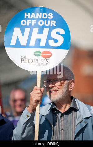 Manchester, UK. 29. September 2013. Ein Mann in seinem fünfziger oder sechziger Jahren hochhalten ein Schild mit der Aufschrift, "Hände weg von unserer NHS", während eine Nord-West TUC organisiert marschieren und Rallye National Health Service (NHS) Arbeitsplätze und Dienstleistungen von Kürzungen und Privatisierungen verteidigen wollte. Der März fällt mit der konservativen Partei Konferenz 2013 in der Stadt statt. Bildnachweis: Russell Hart/Alamy Live News (nur zur redaktionellen Verwendung). Stockfoto