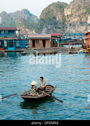 In der Nähe von einem schwimmenden Dorf von Cat Ba Insel im Lan Ha Bucht, Halong Bucht, Vietnam, vietnamesische Mann und Frau in einem Ruderboot. Stockfoto