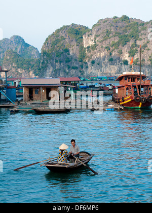 In der Nähe von einem schwimmenden Dorf von Cat Ba Insel im Lan Ha Bucht, Halong Bucht, Vietnam, vietnamesische Mann und Frau in einem Ruderboot.