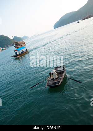 Eine Vietnamesin in einen konischen Hut und ein vietnamesisches Mädchen in einem Ruderboot aus Cat Ba Island in Lan-Ha-Bucht, Halong Bucht, Vietnam. Stockfoto