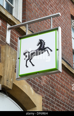 Blickte zu Lloyds Bank schwarzes Pferd Zeichen und Logos oben UK High Street mit Mauer im Hintergrund Stockfoto