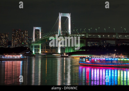 Die beleuchtete Regenbogen-Brücke überspannt Tokyo Bay mit bunten Booten im Vordergrund.  Mintako, Tokyo, Japan. Stockfoto