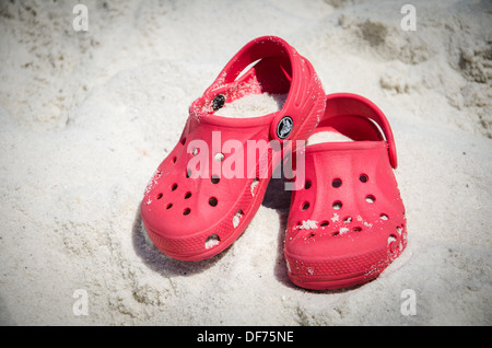 Crocs Schuhe bedeckt im Sand am Strand Stockfoto