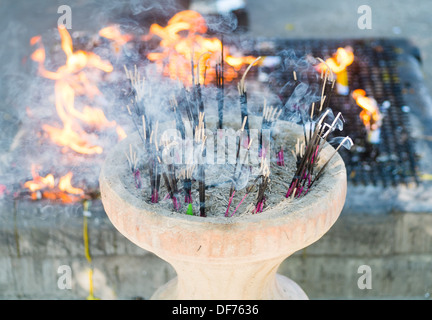 Räucherstäbchen brennt im Topf mit Feuer im Hintergrund Stockfoto