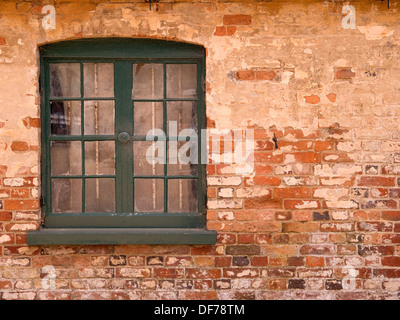 Alte Holzfenster mit Grün lackierten Rahmen inmitten eines alten roten Backsteinmauer, Ticknall, Derbyshire, England, UK Stockfoto