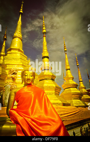 Die unterschiedlche sitzende Buddha-Statue in der Haltung der Meditation und Goldene Pagode. Stockfoto