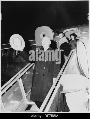 Präsident Harry S. Truman winkt seinen Hut, während er von einer Flugzeugrampe absteigt, und seine Frau Bess und seine Tochter Margaret Truman folgen ihm. Das fängt einen Moment der Präsidentenreise ein. Stockfoto